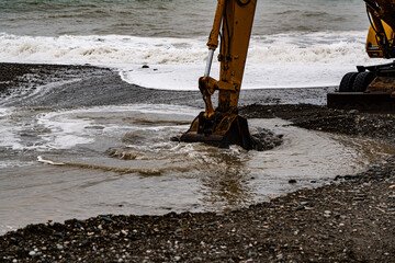 heavy yellow excavator working on the beach