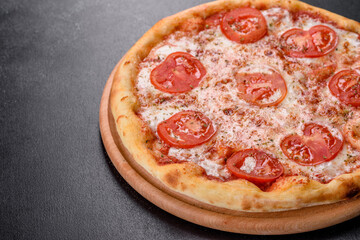 Tasty fresh oven pizza with tomatoes, cheese and basil on a concrete background