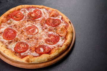 Tasty fresh oven pizza with tomatoes, cheese and basil on a concrete background