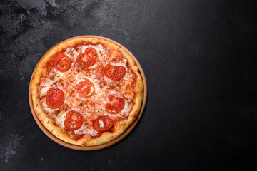 Tasty fresh oven pizza with tomatoes, cheese and basil on a concrete background