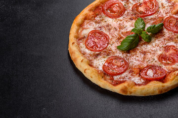 Tasty fresh oven pizza with tomatoes, cheese and basil on a concrete background