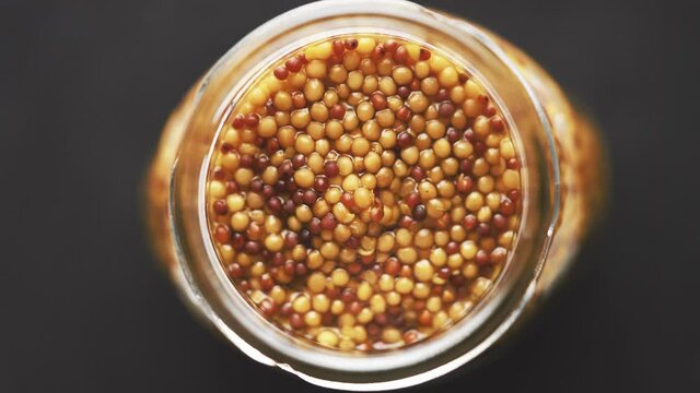 French mustard with whole seeds served in glass jar. Selective focus