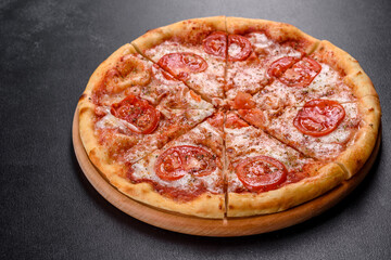 Tasty fresh oven pizza with tomatoes, cheese and basil on a concrete background