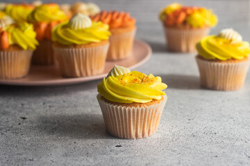 Delicious muffins. Orange and lemon cream muffins. Cupcakes on a concrete table 