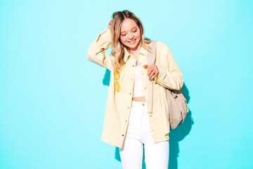 Young beautiful woman looking at camera.Trendy female smiling in casual summer clothes. Positive and funny model posing on grey background in studio with  backpack