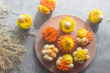Delicious muffins. Orange and lemon cream muffins. Cupcakes on a concrete table 