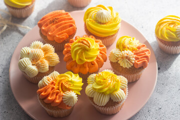 Delicious muffins. Orange and lemon cream muffins. Cupcakes on a concrete table 