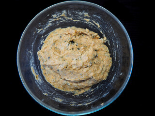 Raw dough for vegan pumpkin muffins gluten-free, egg-free, milk-free in a round glass bowl on a dark table background. View from above