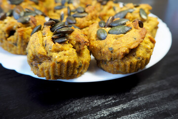 close Vegan muffins with pumpkin gluten-free, egg-free, milk-free stand on a plate on a black table, side view.  diet.  cooking at home