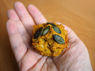 Vegan muffin with pumpkin gluten-free, no egg, no milk is held in the right female hand on the background of a brown table top view. diet. cooking at home