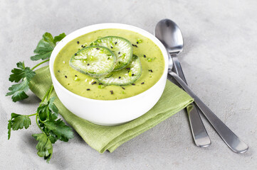 Vegan soup puree green radish potato with parsley in a bowl on a linen napkin on a light background