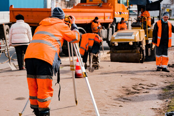 Municipal worker in orange jacket measuring via optical level on construction. Workers. Job....
