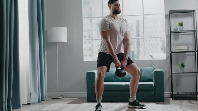 Concentrated muscular guy with beard practices squats
