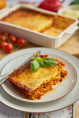 Homemade tasty meat lasagna with fresh basil and parmesan cheese in a plate on wooden background