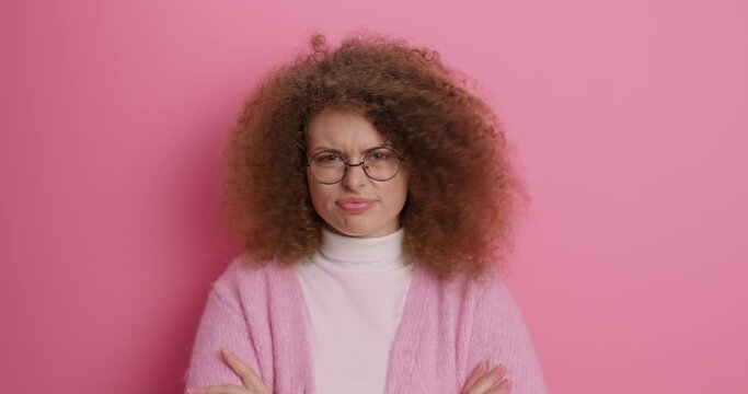 Indignant puzzled woman spreads palms looks with discontent expression smirks face feels dissatisfied while talking and sorting out relationships dressed in casual clothes transparent glasses