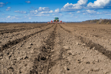 Fototapeta na wymiar tractor with seeder in the field in early spring