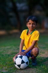 Young boy Sitting in the ground with football 