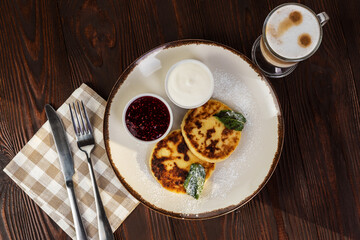 Cheesecakes with sour cream jam and coffee latte on a rustic background. Flat lay