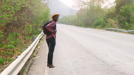 African man traveler  walking on the highway road with backpack