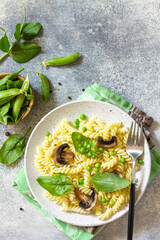 Healthy eating. Pasta fusilli with mushrooms, spinach and green peas on stone table. Vegetarian vegetable mushrooms pasta. Diet menu. Top view flat lay. Copy space.