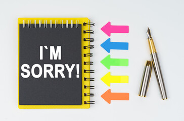 On a white background lies a pen, arrows and a notebook with the inscription - I M SORRY