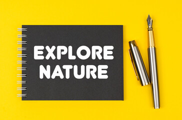 On a yellow background lies a pen and a black notebook with the inscription - Explore Nature