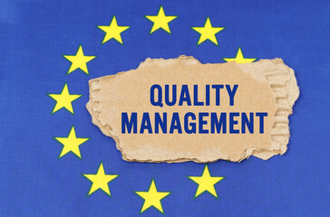 There is a cardboard box on the EU flag that says- QUALITY MANAGEMENT