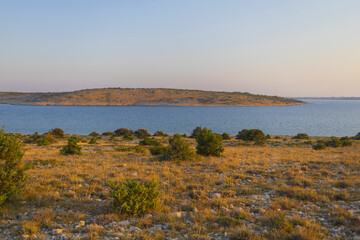 View to small island across rocky land at sunset, Adriatic sea, Dalmatia, Croatia