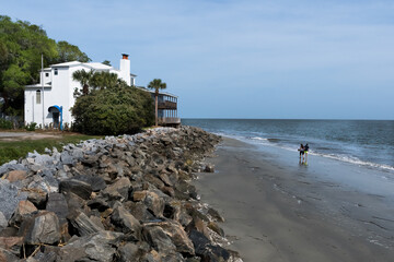 A couple strolls past a secluded home on the Atlantic Ocean shoreline of an island off the Georgia cost at the far southeast corner of the United States