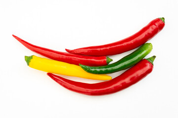 five spicy red, green and yellow chili peppers on white background