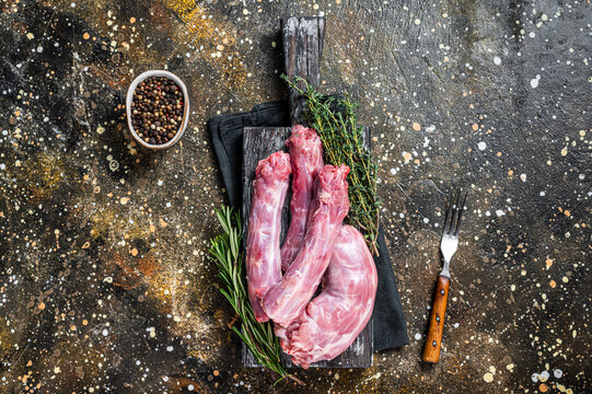 Raw Turkey or chicken necks meat on a wooden board with thyme. Brown background. Top View