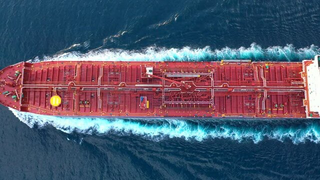 A crude oil tanker underway in open sea. Bow, forecastle, red upper deck, pipe lines, winches, wheelhouse, upper running bridge, radar mast of a supertanker ship on ride. Aerial ocean, flying over
