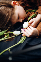 The girl lies in tulips on a dark background. Happy Mother's Day