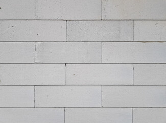 A fragment of a white wall made of blocks, rough masonry, texture or wallpaper