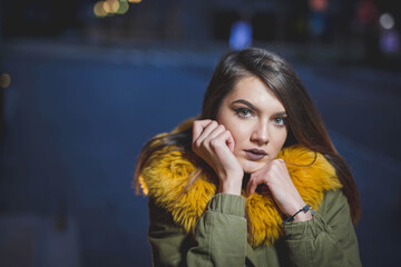 Shallow focus shot of a confident Caucasian female in a puffer posing for the camera