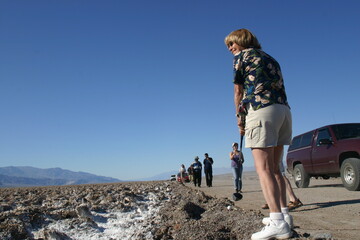 Woman Playing Golf in Death Valley, California, Checking Ready to T-Off at the Devil's Golf Course