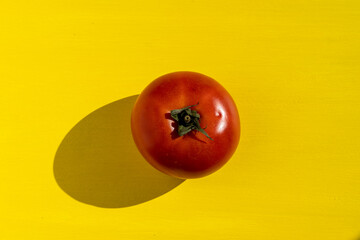 une tomate rouge isolée au centre, sur un fond jaune