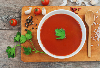 Delicious tomatoes soup on dark rustic wooden table.