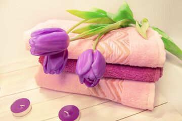 Obraz na płótnie Canvas Spa still life - tulips, candles, towels on a white wooden background. Beige, pink, lilac, purple and white tones.