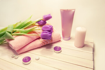 Obraz na płótnie Canvas Spa still life - tulips, candles, shower accessories and towels on a white wooden background. Beige, pink, lilac, purple and white tones.