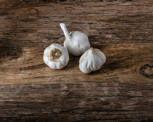 Three fresh garlic bulbs on a wooden table - 428494344