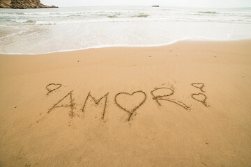 Words written on the sand on the beach, the sign says ... happiness, sea, be yourself, universe, god, travel, happy, love