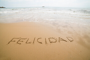 Words written on the sand on the beach, the sign says ... happiness, sea, be yourself, universe, god, travel, happy, love