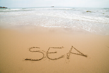 Words written on the sand on the beach, the sign says ... happiness, sea, be yourself, universe, god, travel, happy, love