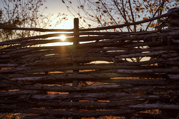 Wicker fence in the backdrop of a sunset sky. Handmade, decoration garden. Rustic style. Ecology house.