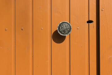 An orange-colored wooden door with a metal handle and a keyhole