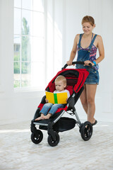 Caucasian young woman pushing stroller with toddler boy indoors