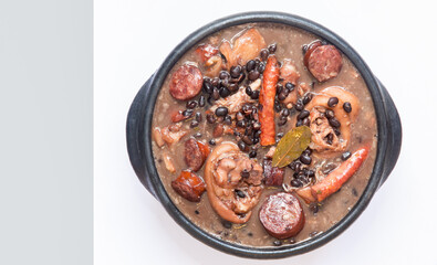 Typical Brazilian feijoada in black clay pot, top view. Black beans, pork sausage, traditional seasoning