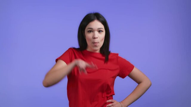 Attractive woman dancing on violet studio background. Girl in red basic wear. Positive mood. Slow motion.