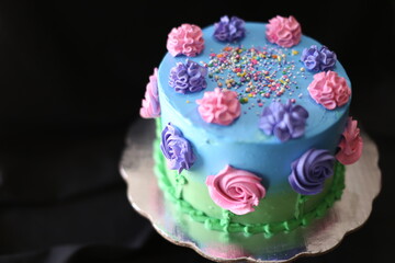 Pastel de cumpleaños decorado con flores de azucar, azul, chispas, verde, pasto